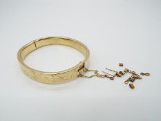 A hallmarked 9ct yellow gold bangle with safety chain and chased,