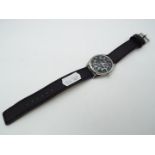 A military style wristwatch, black dial with green numerals marked hmt,