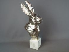 A chrome rabbit's head on marble base,