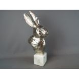A chrome rabbit's head on marble base,