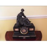 A French marble cased mantel clock surmounted by a bronze figure depicting a seated female figure