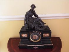 A French marble cased mantel clock surmounted by a bronze figure depicting a seated female figure