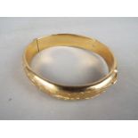 A hallmarked 9ct gold bangle with safety chain (several dents and somewhat misshapen),