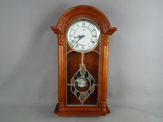 An Acctim wall clock, with pendulum.