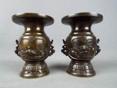 A pair of twin handled bronze vases, with bird and turtle decoration, white metal inlay,