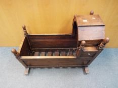 A late Georgian / early Victorian child's rocking crib with hinged hood and turned finials