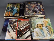 A box of 12" vinyl records to include The Beatles, ABBA, The Eagles, The Moody Blues,
