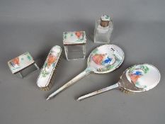 A George VI dressing table set comprising a silver and enamel backed mirror and three dressing
