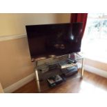 A Panasonic lcd Television set model TX-48CX400B with accessories on glass TV stand (qty)