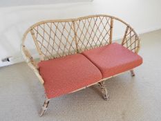 A two-seater bamboo couch with red upholstered seat cushions