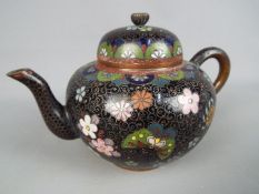 A small cloisonné teapot with floral decoration on a black ground, approximately 10.5 cm (h).