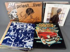 A collection of 12" vinyl records to include Judas Priest, Status Quo, Erasure, The Beach Boys,