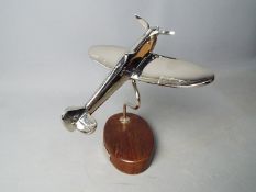 A plated model of a Spitfire mounted on a wooden plinth,