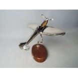 A plated model of a Spitfire mounted on a wooden plinth,