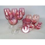 A collection of cranberry glassware including a Mary Gregory type beaker with enamel decoration of