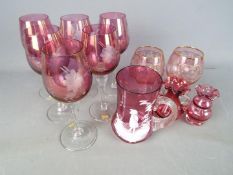 A collection of cranberry glassware including a Mary Gregory type beaker with enamel decoration of
