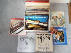 A collection of 12" and 7" vinyl records to include The Beatles, Wings, John Lennon, The Carpenters,