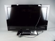 A Toshiba 32" flatscreen television, model 32BV702B with remote and instructions.