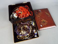 A Japanese lacquered box containing predominantly costume jewellery including bead necklaces,