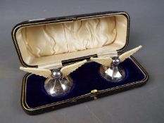 A pair of George V hallmarked silver and bone knife rests in the form of wings on splayed bases,
