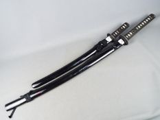 Two reproduction Japanese swords with black lacquered saya, longest approximately 109 cm.