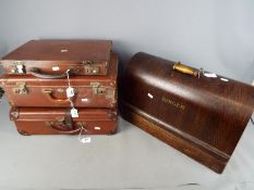 A vintage Singer sewing machine and three small vintage cases.