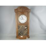 An oak cased wall clock with pendulum.