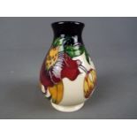 Moorcroft Pottery - a vase decorated in the Anna Lily pattern, printed factory label to the base,