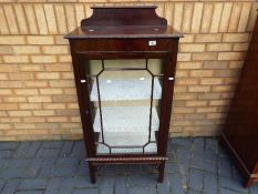 A display cabinet with carved detailing and twin glass shelves,