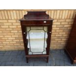 A display cabinet with carved detailing and twin glass shelves,