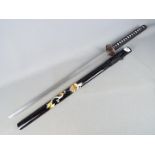 A reproduction Japanese sword with black lacquered, dragon decorated saya and dragon tsuba,