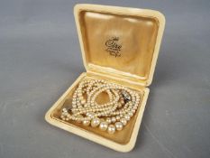A triple strand, graduated pearl necklace with white metal, stone set clasp,