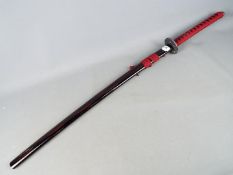 A reproduction Japanese sword with black lacquered saya, approximately 104 cm total length.