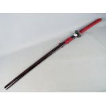 A reproduction Japanese sword with black lacquered saya, approximately 104 cm total length.