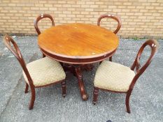 A circular topped table on carved support with four chairs.