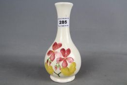 A Moorcroft solifleur vase hand painted in a floral design on a cream ground,
