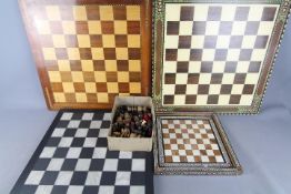 A quantity of assorted chess pieces and chess boards, largest board approximately 51 cm x 51 cm.