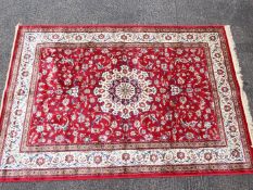 A red ground Kashmir carpet / rug with medallion pattern, approximately 240 cm x 160 cm.