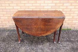 Gateleg Table - a George II oak gateleg table, the oval twin flap top above an end frieze drawer,