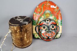 An animal skin drum and a painted tribal mask.