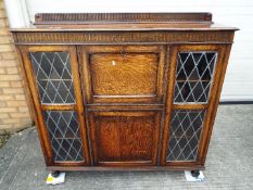 A freestanding bookcase with twin glazed doors flanking a central cupboard section,