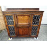 A freestanding bookcase with twin glazed doors flanking a central cupboard section,