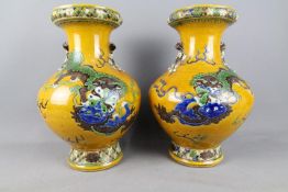 A pair of Chinese vases decorated with Guardian Lion and cubs against a yellow ground,