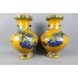 A pair of Chinese vases decorated with Guardian Lion and cubs against a yellow ground,