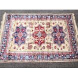 A cream ground Kashmir carpet / rug with an Aztec style design, approximately 240 cm x 160 cm.