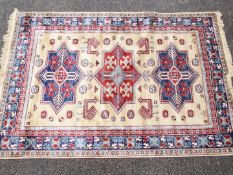 A cream ground Kashmir carpet / rug with an Aztec style design, approximately 240 cm x 160 cm.