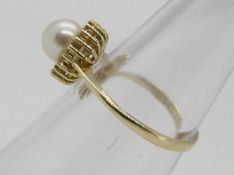 A 14ct yellow gold ring set with single pearl and diamond chip surround, size M + ½,