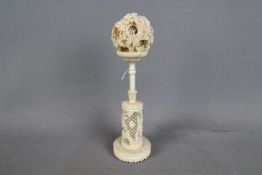 An early 20th century carved ivory puzzle ball and stand,