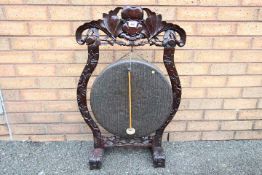 A Victorian Dinner Gong and beater in carved hardwood frame,