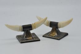 An Edward VII pair of silver and ivory knife rests formed as a pair of horns on a square base,